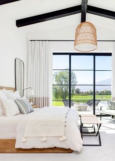 a bedroom with white walls and flooring has a large window that looks out onto the golf course