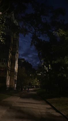 a dark street at night with people walking on the sidewalk