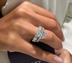 a woman's hand with a diamond ring on her left hand and an engagement band