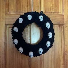 a wreath with skulls on it hanging from the front door, decorated with black felt