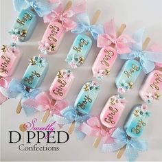 candy pops decorated with bows and the word boo spelled on them in blue, pink, and gold