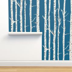 the wall paper has been painted with white birch trees on blue and is next to a roll of toilet paper