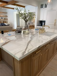 a kitchen island with marble counter tops and gold faucets in the center area