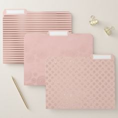 three pink file folders next to a pen and pencil on a white table top