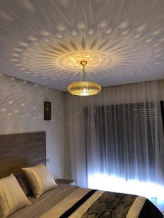 a bedroom with a large bed and a chandelier hanging from the ceiling above it