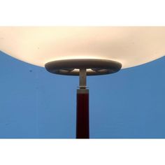 a lamp that is on top of a red pole with a blue sky in the background