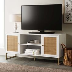 a flat screen tv sitting on top of a white entertainment center with wicker doors