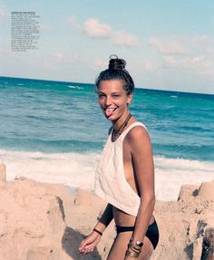 a woman standing on top of a sandy beach next to the ocean