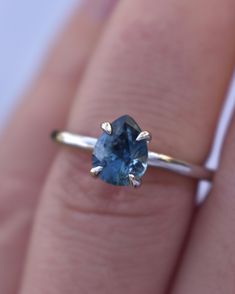 a woman's hand with a ring on it and a blue stone in the middle