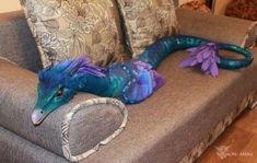 a blue and purple dragon laying on top of a couch