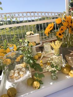 a table topped with lots of yellow flowers and lemons on top of a white table