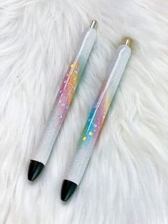 two pens sitting on top of a white fur covered floor next to eachother