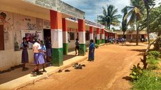 several people standing in front of a building on a dirt road