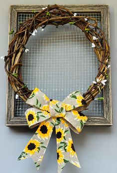 a wreath with sunflowers tied to the front of it and hanging on a wall