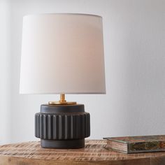 a lamp sitting on top of a wooden table next to a book and a box