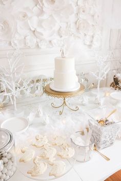 a white cake sitting on top of a table covered in frosted sugar cookies next to other desserts