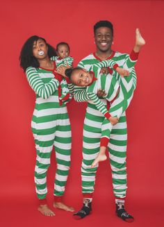 three people dressed in green and white striped onesuits, one holding a baby