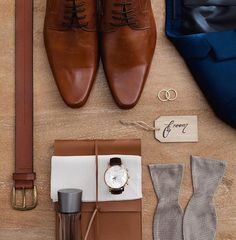 men's clothing and accessories laid out on the ground with shoes, watch, tie, wallet, coffee cup, pocket knife