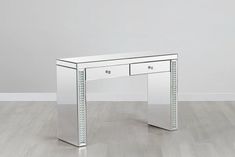 a mirrored desk with two drawers on the top and one drawer at the bottom, in front of a white wall