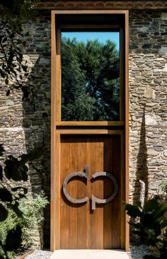 a wooden door with an iron ring on it and trees in the backround