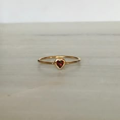 This Garnet Heart Ring brings love with you wherever you go. Show someone you love that you always have them in your heart. A great gift ring! Details: 14k gold (available in yellow, rose or white gold)Garnet heart measures about 3mm Free Shipping on Domestic Orders Materials: Garnet, 14k gold Need your ring bigger tha