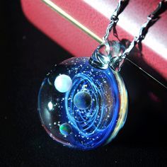 a glass ball with an image of the solar system in it on a silver chain