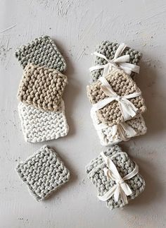 four crocheted coasters tied together with white ribbons and bows on a table