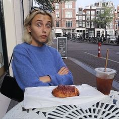 a woman sitting at an outdoor table with a pastry in front of her