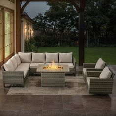 an outdoor living area with couches, tables and fire pit in the middle of it