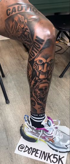 a man's leg with tattoos and sneakers on top of the floor in front of him