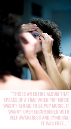 a shirtless man looking at his reflection in the mirror