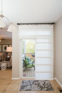 an open door leading to a living room with a green chair and rug on the floor