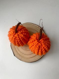 two orange knitted pumpkins sitting on top of a piece of wood