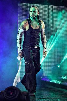 a man with green paint on his face walking down a runway