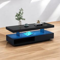 a black coffee table sitting on top of a hard wood floor next to a plant