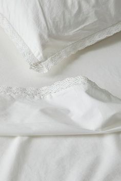 two white pillows with lace trims on them