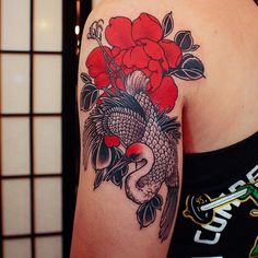 a woman with a tattoo on her arm holding a red rose and koi fish