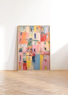 an abstract painting on the wall next to a chair in a room with hard wood flooring