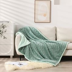 a white couch with a green blanket on it