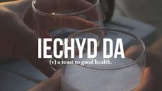 a person holding a glass with ice in it and the words lechyd da above it