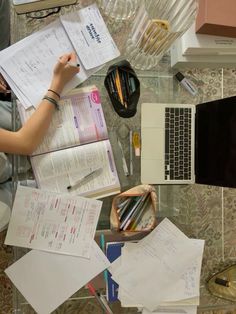 a desk with papers, pens and laptop computer on it next to other office supplies