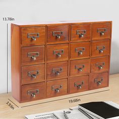 a large wooden cabinet with drawers next to a notebook and pen on a table in front of it