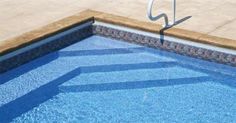 an empty swimming pool with blue water and tile around the edge is pictured in this image