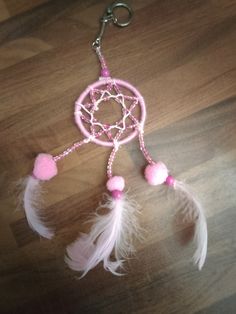 a pink and white dream catcher on a wooden table