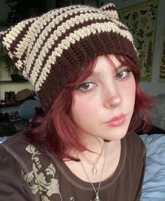 a woman with red hair wearing a brown and white striped knitted beanie hat