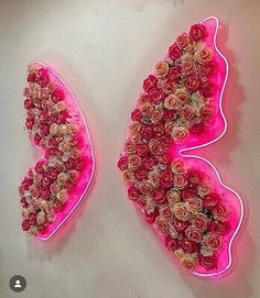 two pink butterflies made out of flowers on a wall