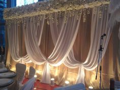 an image of a wedding stage set up with white chairs and flowers on the head table