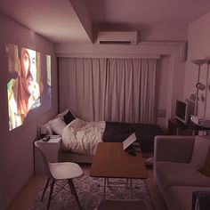 a living room with a couch, table and television in the corner on the wall