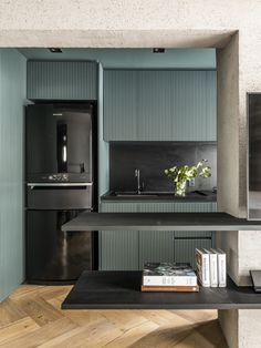 a kitchen with green painted walls and wooden flooring, along with books on the table