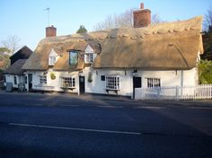 a white house with a thatched roof next to a street